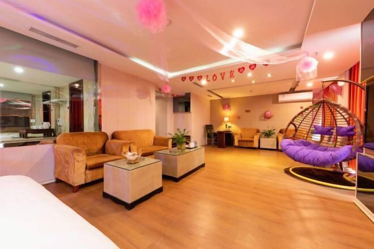 Moderni hotellihuone, jossa on sohva, sohvapöytä, riipputuoli ja peili.