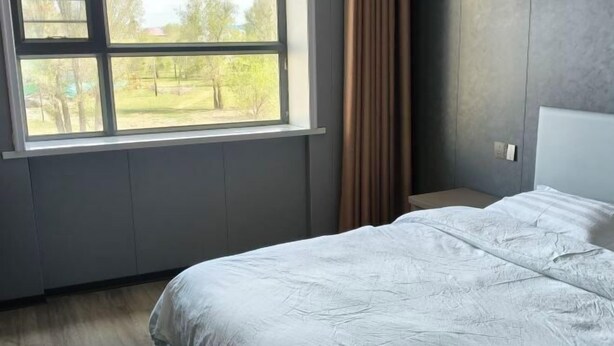 Une chambre avec un grand lit, une fenêtre avec des rideaux et une vue sur un parc.