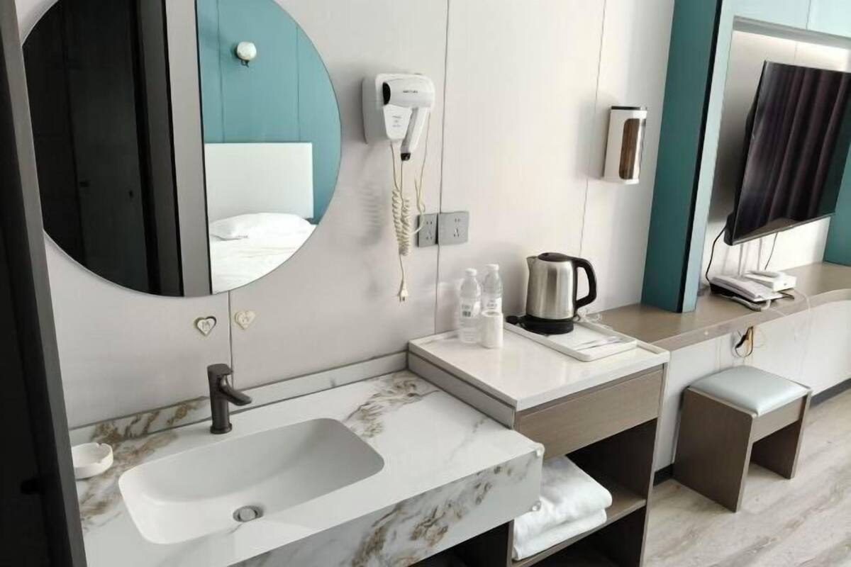 Een moderne badkamer met een wastafel, spiegel, haardroger en een televisie aan de muur.