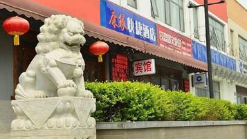 Une statue de lion se trouve devant un bâtiment doté d’un auvent rouge et d’une enseigne.