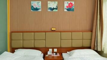 Habitació d'hotel amb dos llits, un capçal de llit de fusta i tres quadres florals a la paret.