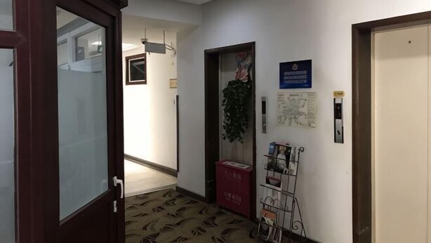 Un pasillo con una puerta de madera, una caja roja, un mapa y un soporte para bicicletas.