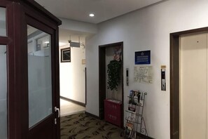 A hallway with a wooden door, a red box, a map, and a bike rack. - Kangyuan Express Hotel Beijing (Beijing)