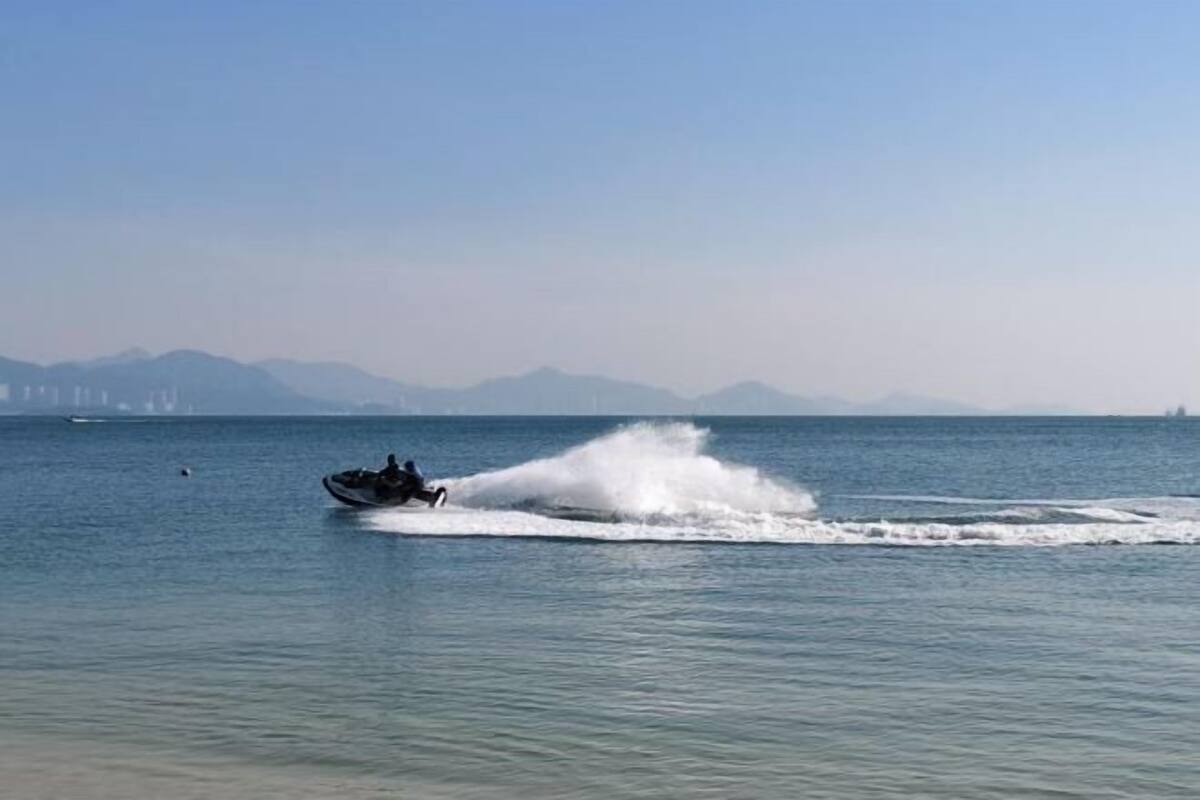 A jet ski on calm water with distant mountains and a clear sky.
