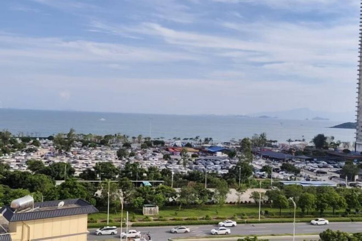 A coastal cityscape with a marina, parked cars, and buildings.
