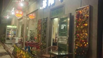 A storefront with a sign indicating a business, a chair outside, and a decorative wall.