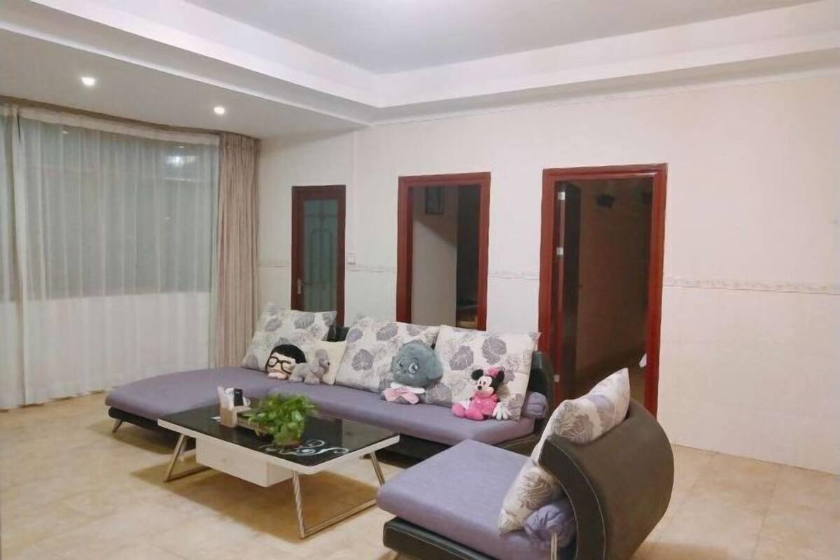 A modern living room with a sofa set, a coffee table, and a large window with curtains.