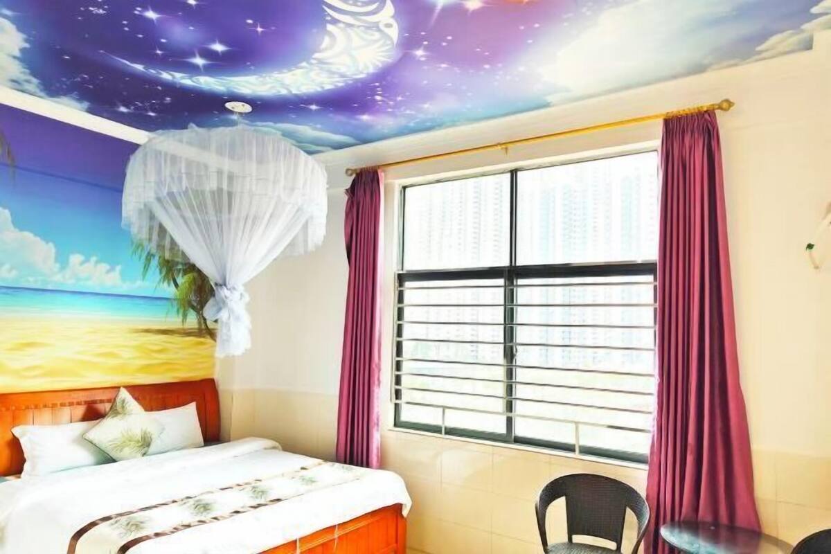 A room with a bed, a window with blinds, a chair, and a ceiling mural.
