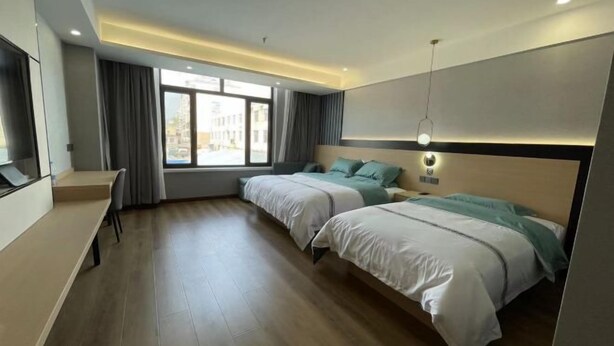 A modern hotel room with two beds, a desk, and a large window.