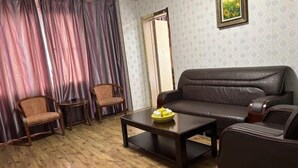 A living room with a sofa, two chairs, a coffee table, and a door.