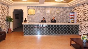A reception area with a patterned wall, a reception desk, and a clock.