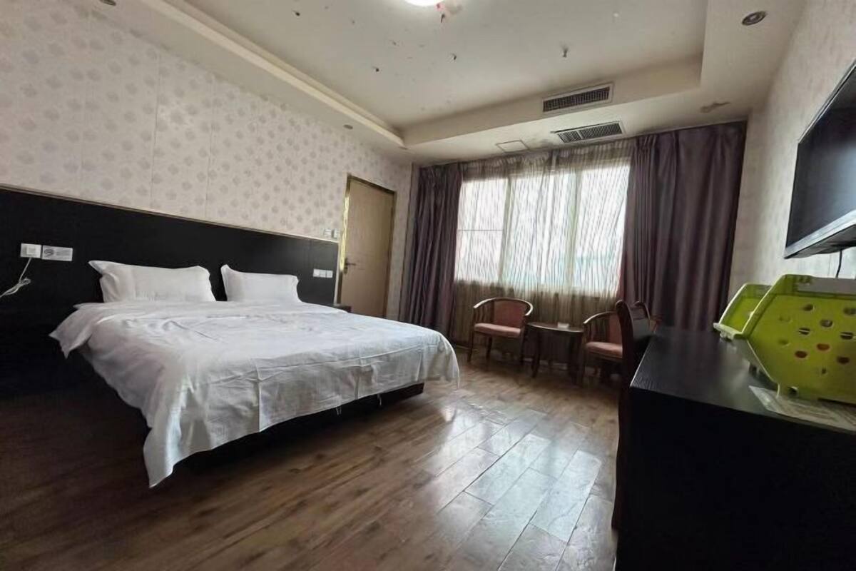 Una habitación de hotel con cama, escritorio, silla y televisor.