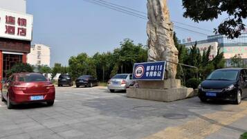 Een parkeerplaats met auto's, een stenen monument en een bord dat een hotel aangeeft.