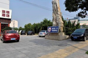 Un área de estacionamiento con automóviles, un monumento de piedra y un letrero que indica un hotel.
