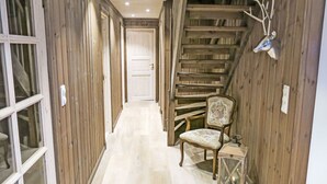 A wooden hallway with a staircase, a chair, and a lantern.