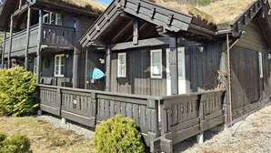 A wooden chalet with a balcony and a thatched roof.