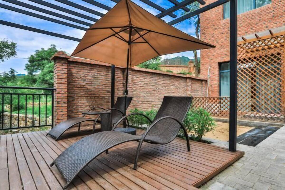 A wooden deck with two metal chairs and a large umbrella.