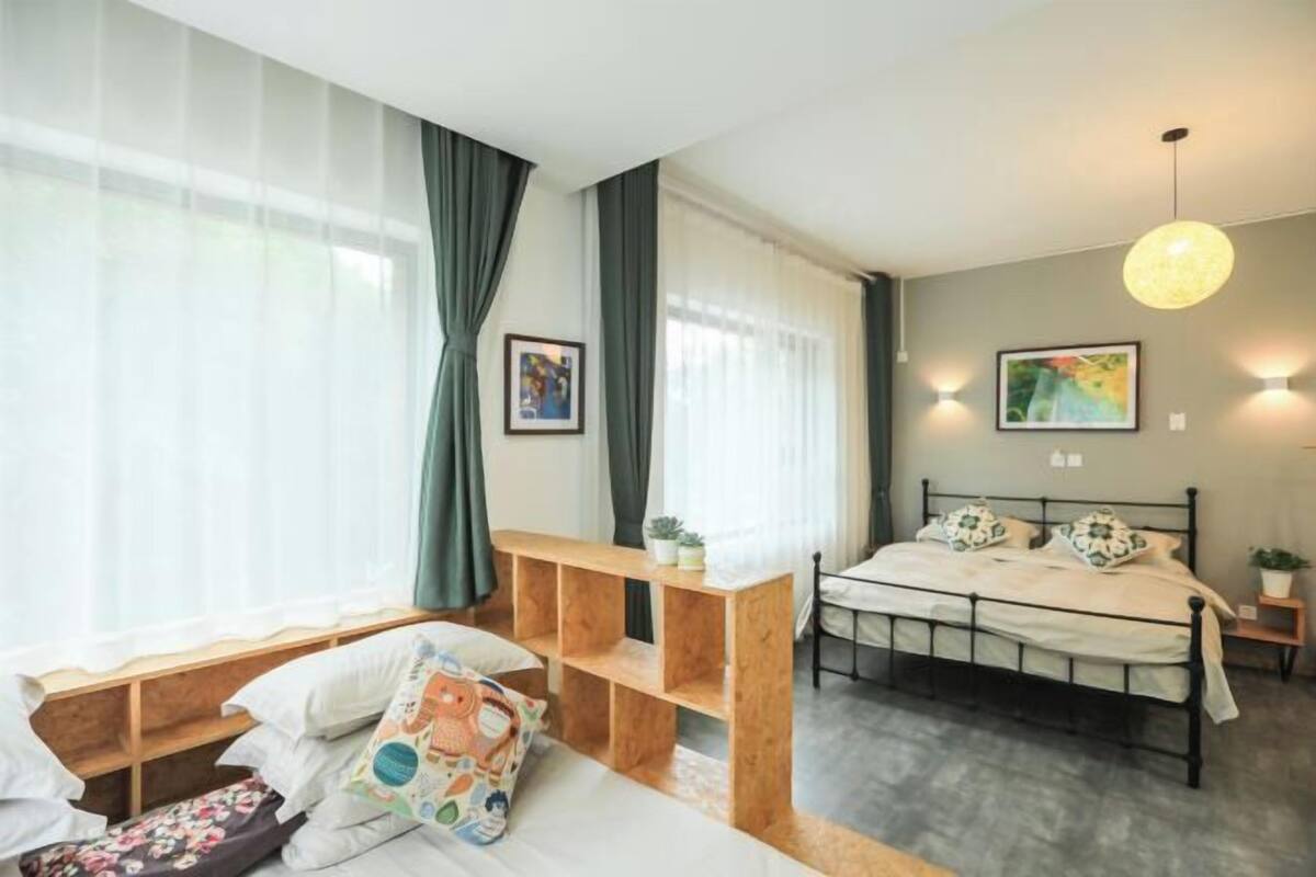 A bedroom with a bed, a wooden bench, a bedside table, and a wall-mounted light fixture.