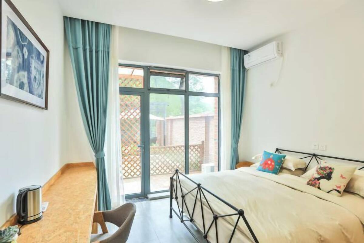 A bedroom with a bed, a chair, a table, and a window.