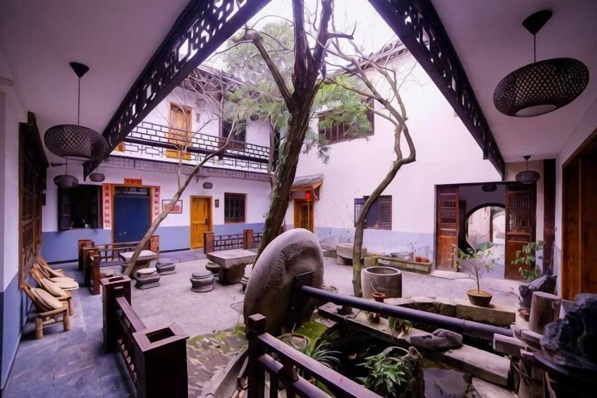 A courtyard with a traditional design, featuring a wooden bench, a stone table, and a potted plant.