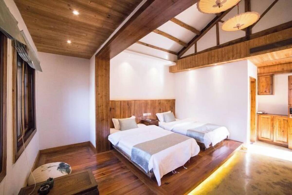 A room with wooden beams, two beds, a wooden floor, and a small table.