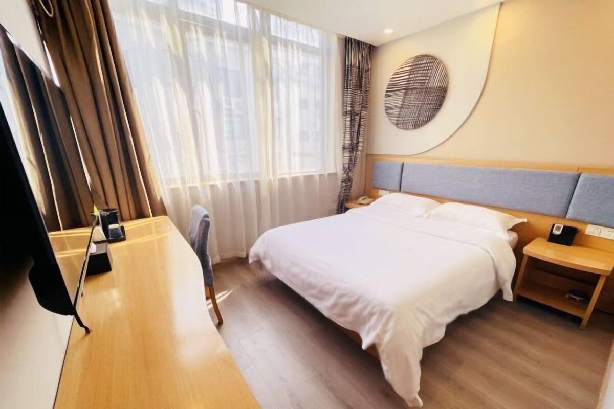 A hotel room with a large bed, a desk, and a chair.