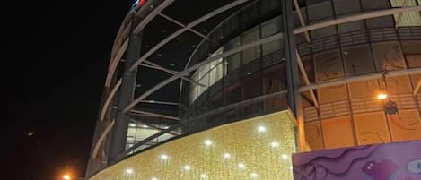 A building with a curved facade, illuminated by string lights and a large illuminated sign.