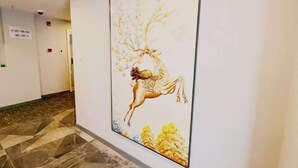 A corridor with a large framed artwork depicting a woman riding a horse, a patterned floor, and a door with a sign. - EasyGo Motel (Shanghai Dahua Hucheng Branch) (Shanghai)
