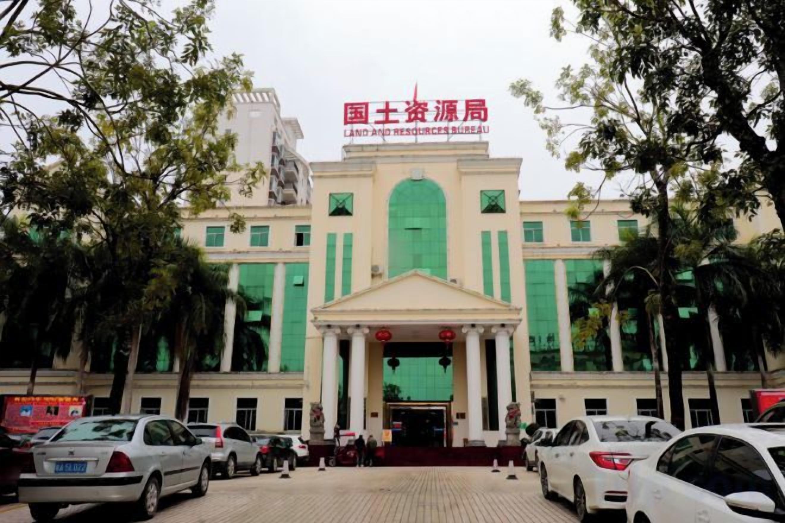 A building with a green entrance and a sign above it. There are cars parked in front.