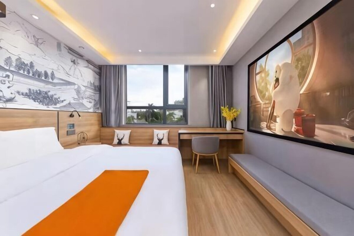 Ein modernes Hotelzimmer mit einem großen Bett, einem Schreibtisch, einem Fenster mit Aussicht und einem Wandbild.