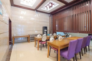 Un comedor de hotel con una mesa de madera, sillas moradas y un diseño de techo moderno.