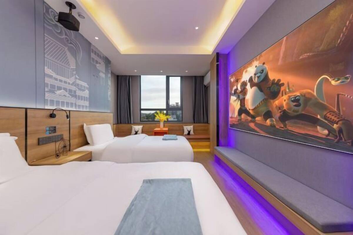 A hotel room with two beds, a large wall mural, and a cityscape design on the wall.