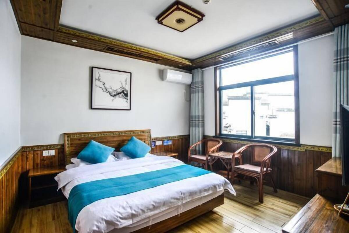Quarto de hotel com cama, uma cadeira, janela e ar-condicionado fixado na parede.