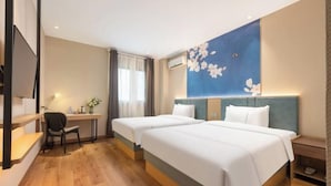 A hotel room with two beds, a desk, a chair, and a large floral wall decoration. - Jinjiang Inn (Shanghai Zhihui Yuan Qu Hulan Road Metro Station) (Shanghai)