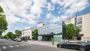 A modern building with a glass facade, a visible entrance, and a parking area with cars. - Jinjiang Inn (Shanghai Zhihui Yuan Qu Hulan Road Metro Station) (Shanghai)