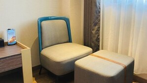 A corner of a room with a blue-framed chair and a matching ottoman, a small table with a phone and a brochure, and a window with sheer curtains. - Jinjiang Inn (Shanghai Zhihui Yuan Qu Hulan Road Metro Station) (Shanghai)