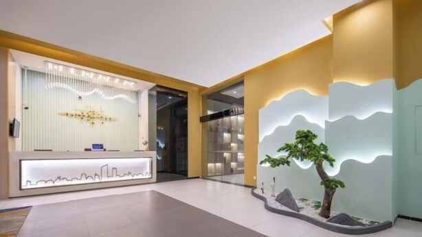 A modern reception area with a digital display, a reception desk, and a decorative wall with a tree and landscape design. - Jinjiang Inn (Shanghai Zhihui Yuan Qu Hulan Road Metro Station) (Shanghai)