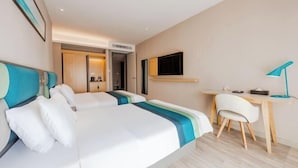 Ein Hotelzimmer mit zwei Betten, einem Schreibtisch, einem Stuhl, einem Fernseher und einer Tür zu einem Badezimmer.