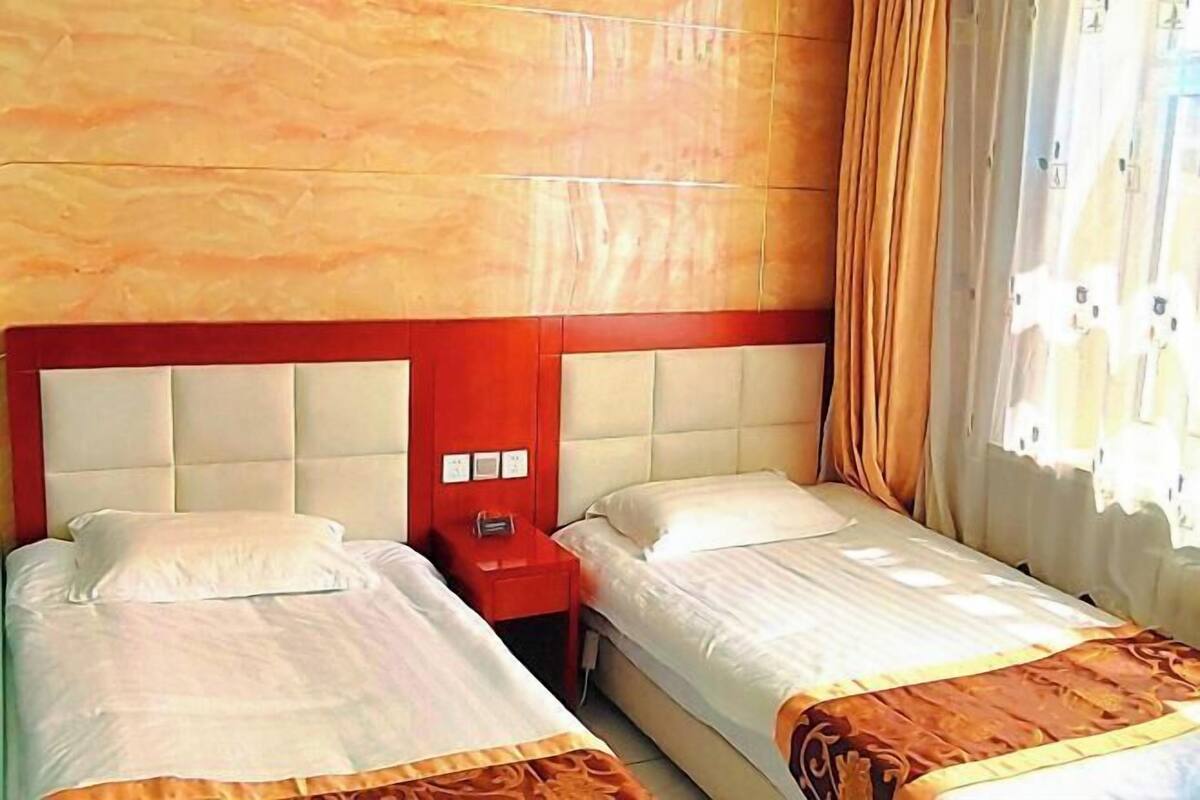 Ein Hotelzimmer mit zwei Betten, einem roten Nachttisch und einem hölzernen Kopfende.