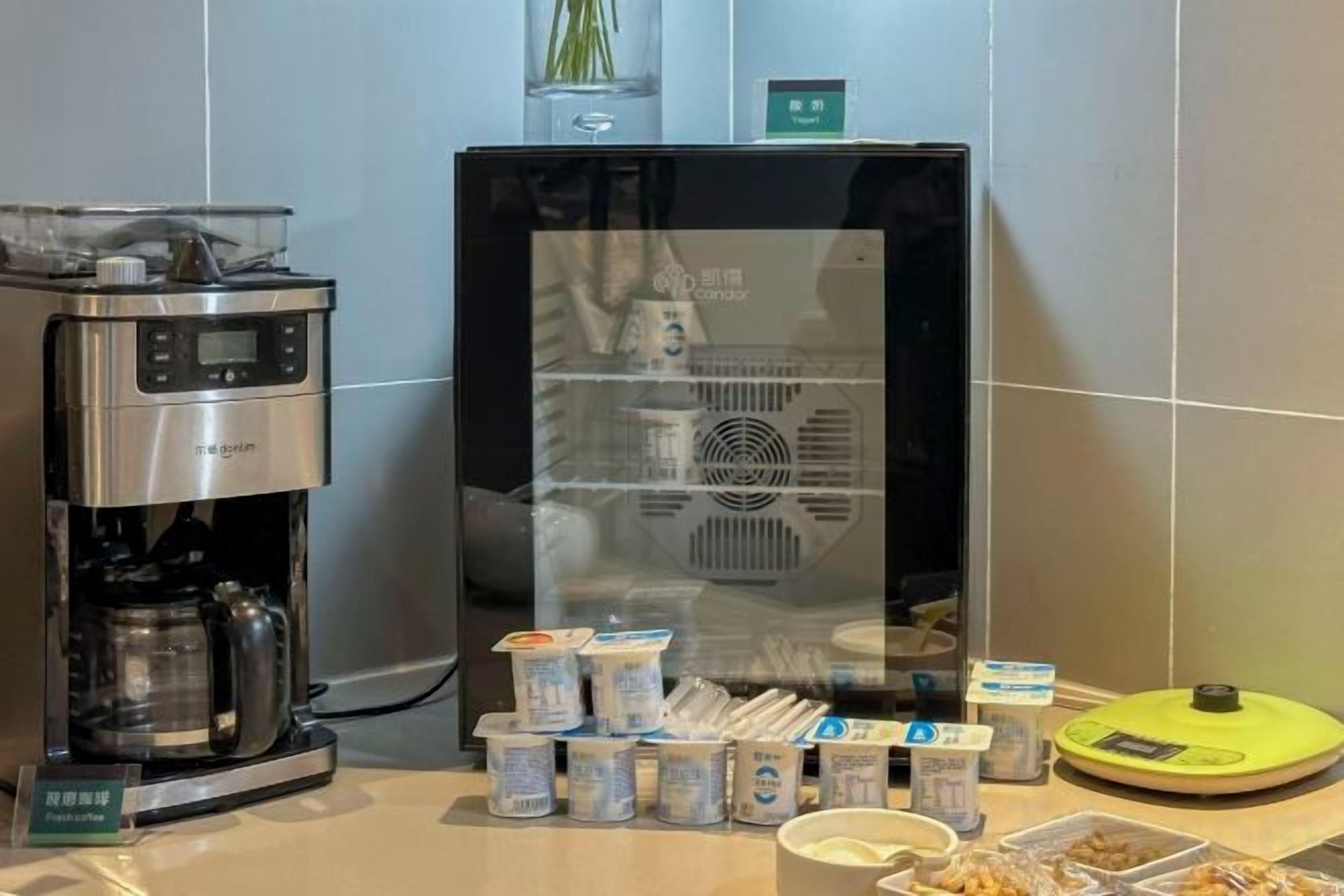 Una máquina de café y un refrigerador con diversos alimentos y recipientes sobre una encimera.
