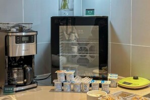 A coffee machine and a refrigerator with various food items and containers on a countertop.