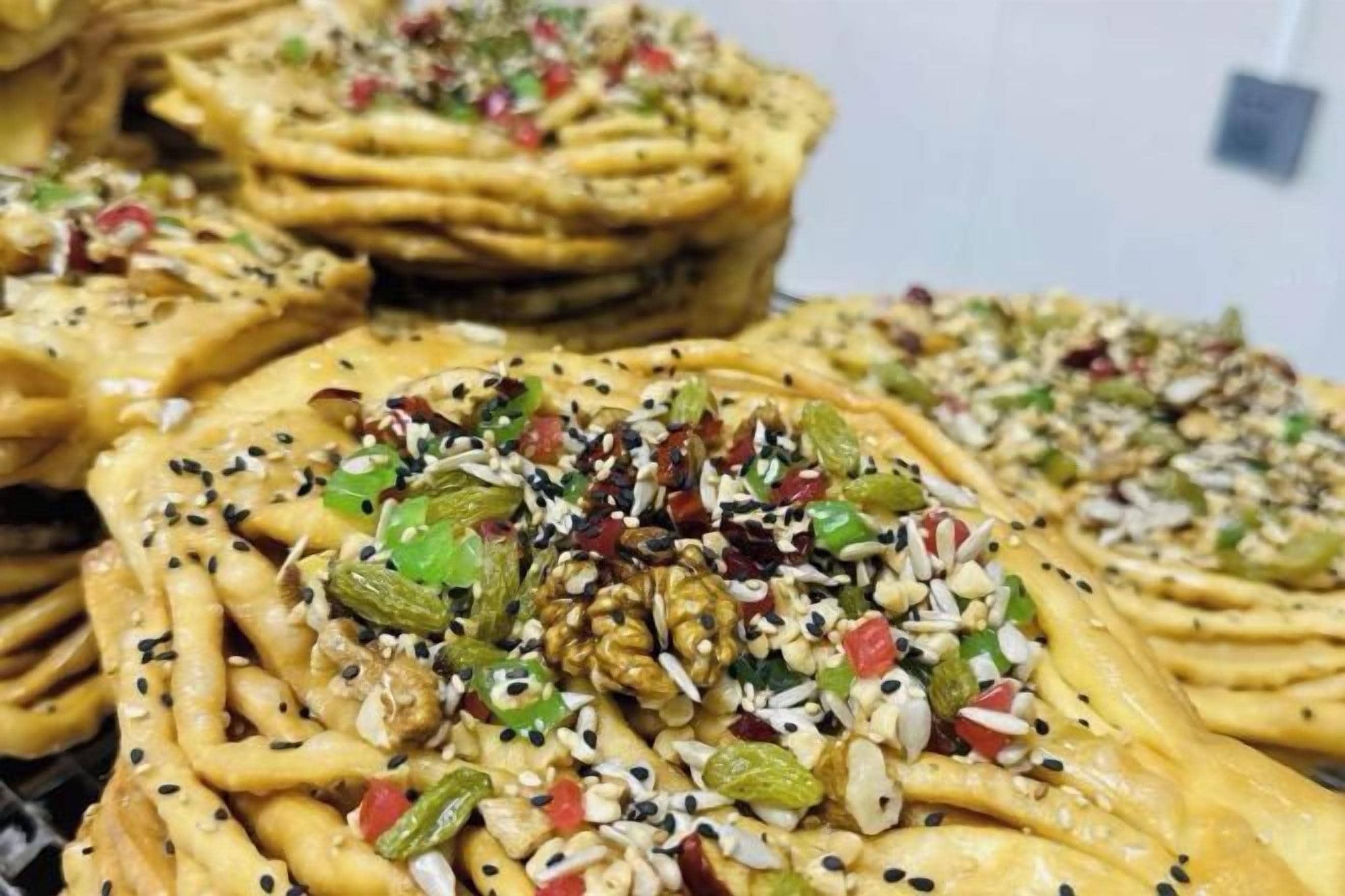 A stack of flatbreads topped with various seeds and chopped vegetables.