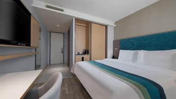 A modern hotel room with a bed, a desk, and a TV.
