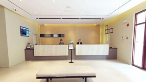 Een receptie met twee balies, een bank en een groot raam.