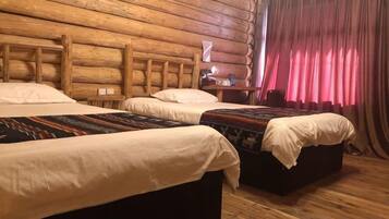 A log cabin-style room with three beds, wooden walls, and a red curtain.
