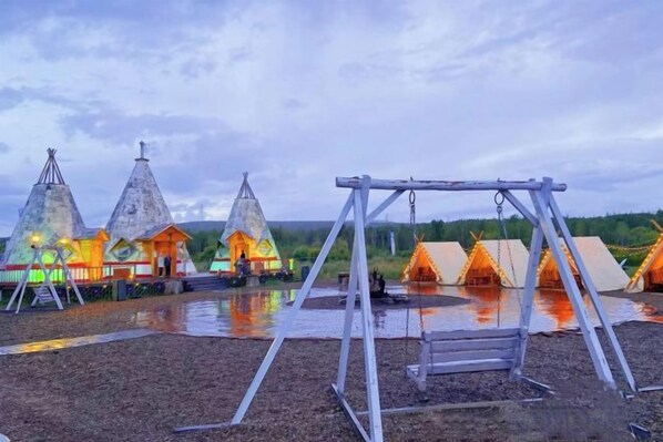 A series of conical tents with a swing set in the foreground.