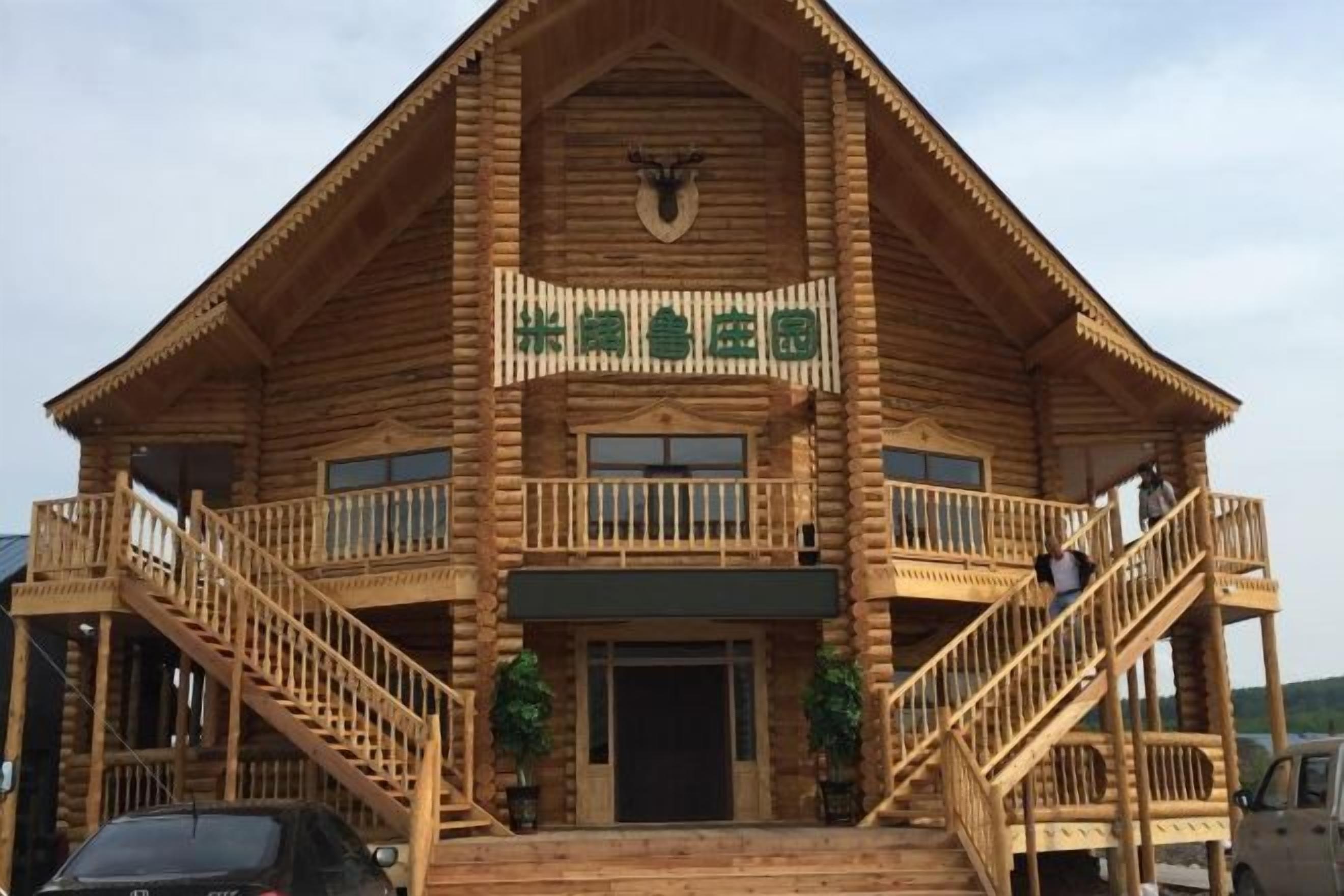 A wooden lodge with a balcony, a staircase, and a sign above the entrance.