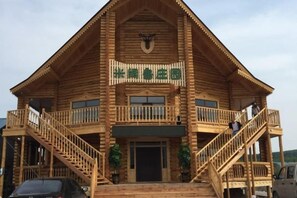 A wooden lodge with a balcony, a staircase, and a sign above the entrance. - Mikuolu Manor (Ergun)