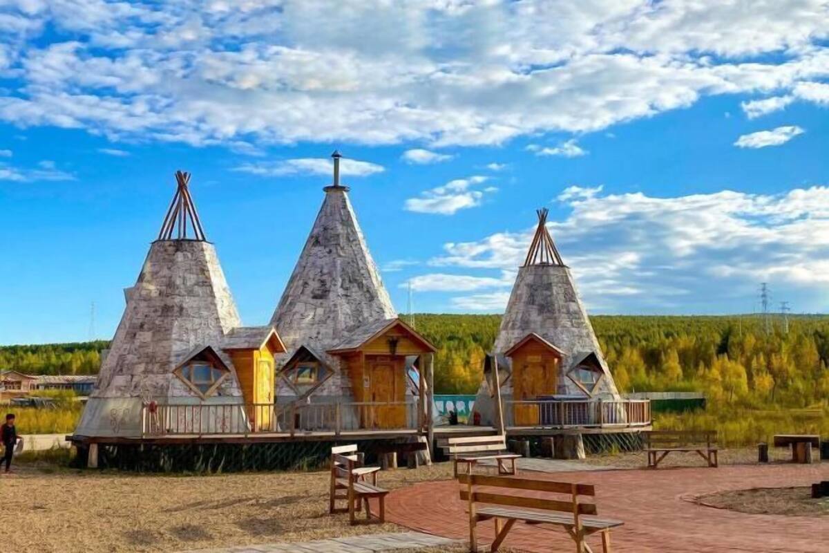 Three conical wooden structures with wooden decks and benches.