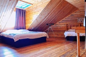 Una camera da letto con soffitto a falde, un letto, un tavolino e un cavalletto.